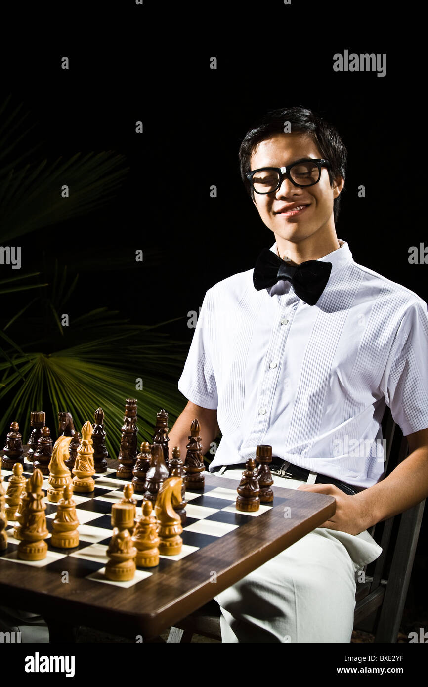 Mixed race geek playing chess Stock Photo