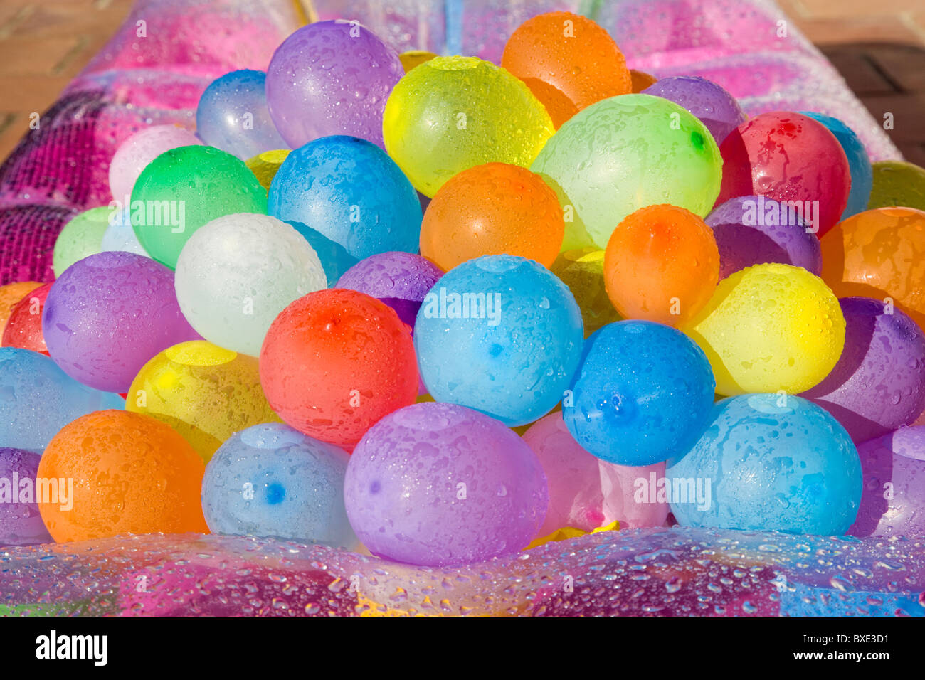Multicolored water filled colored balloons laying on a moistened air-bed Stock Photo