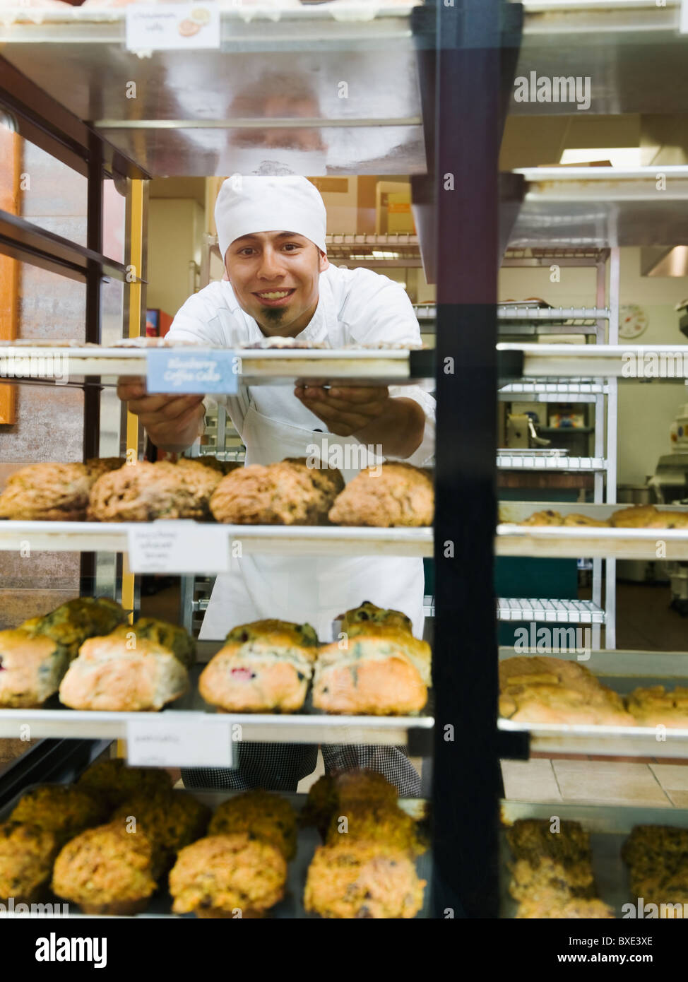 Baker standing behind trays of baked goods Stock Photo