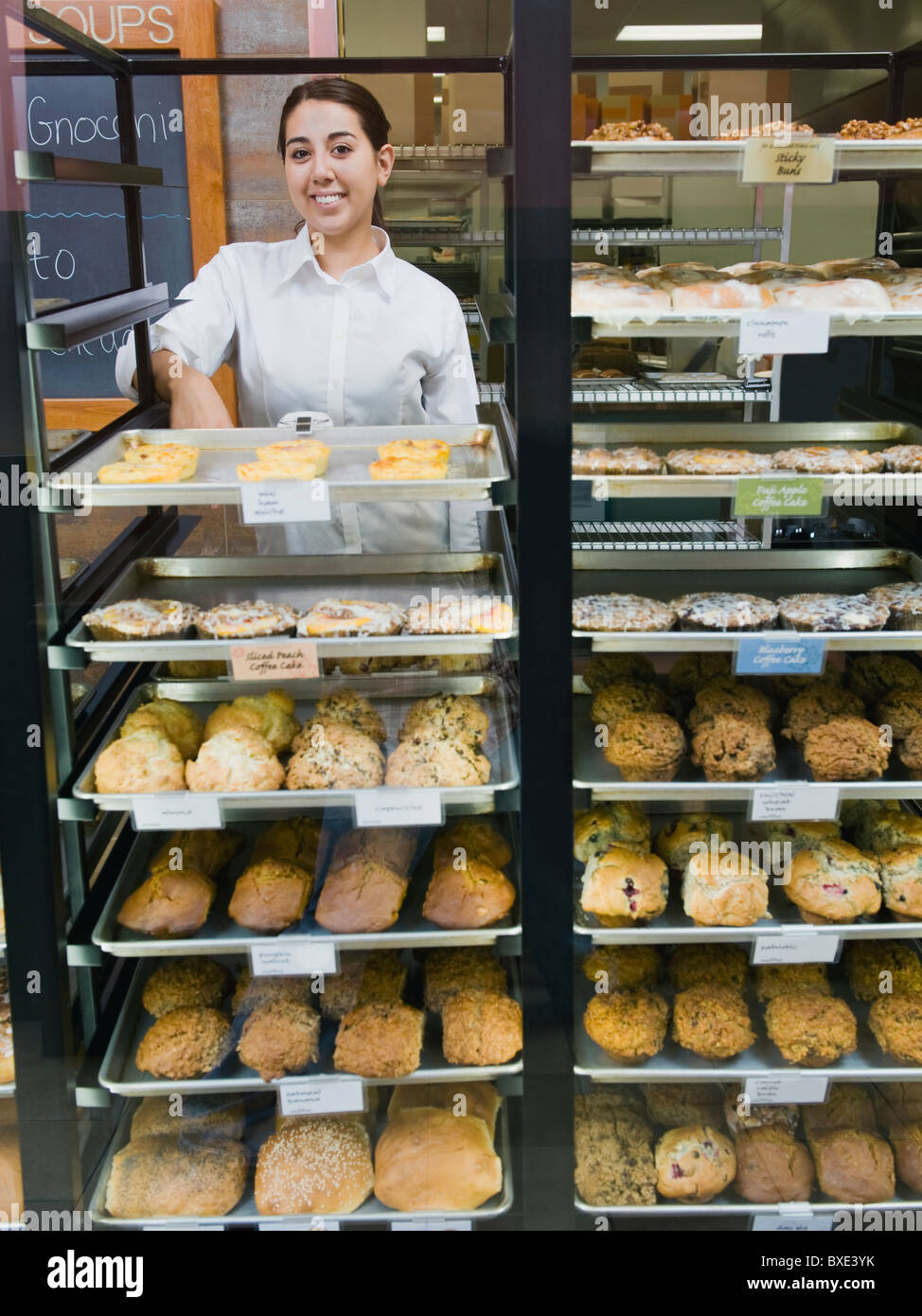 Baker standing behind trays of baked goods Stock Photo