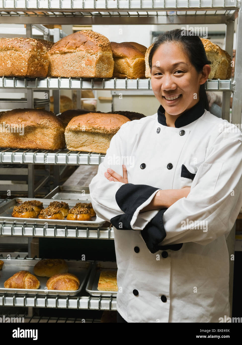 Chef standing beside trays of freshly baked goods Stock Photo
