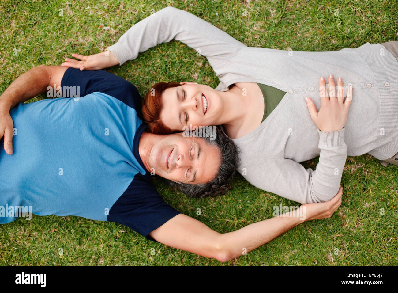 Happy couple relaxing on the grass together Stock Photo - Alamy
