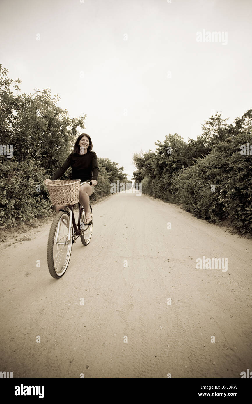 Woman biking on small rural road Stock Photo