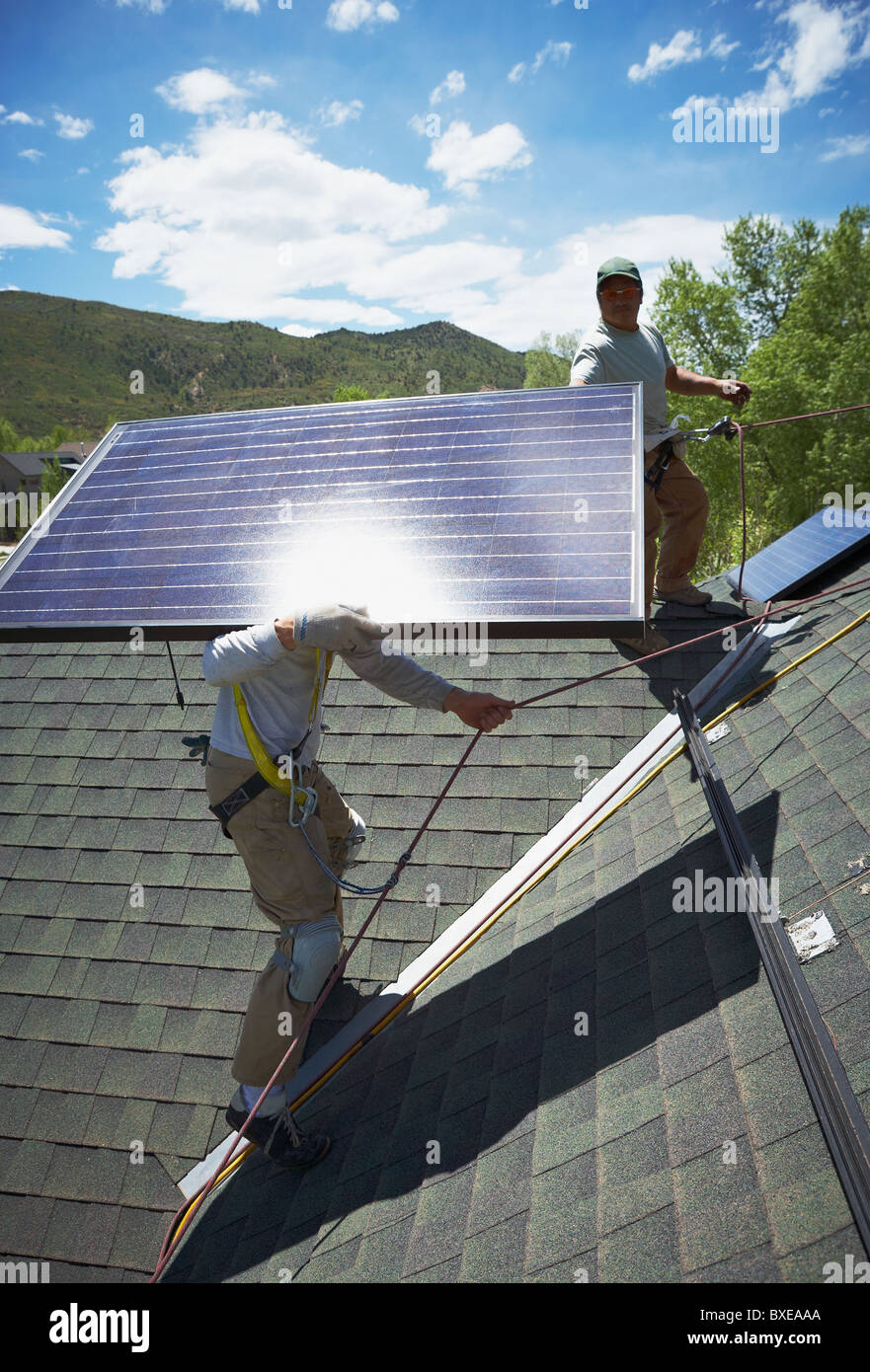Construction workers installing solar panels on roof Stock Photo