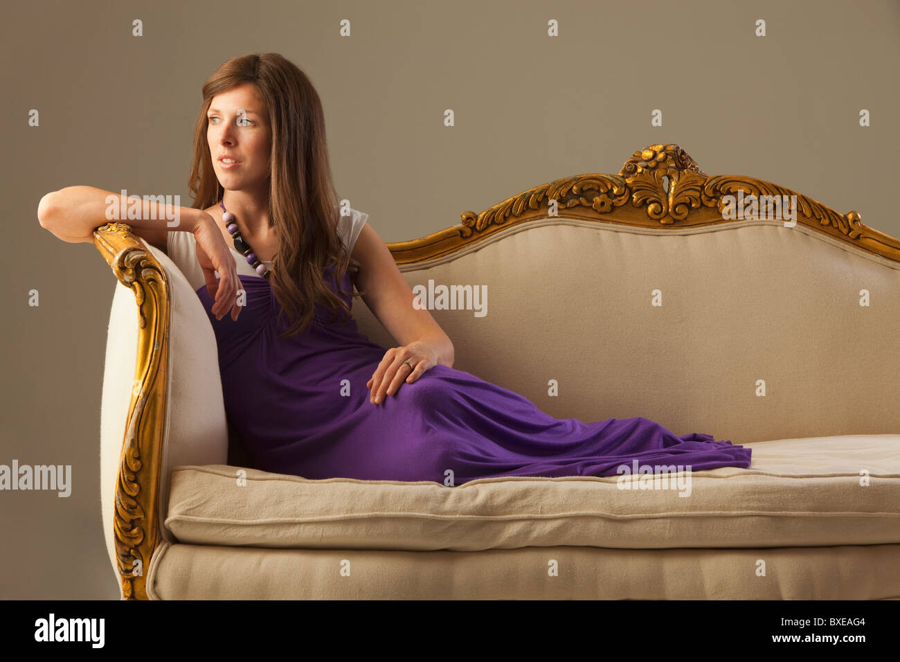 Elegant woman lounging on antique sofa Stock Photo