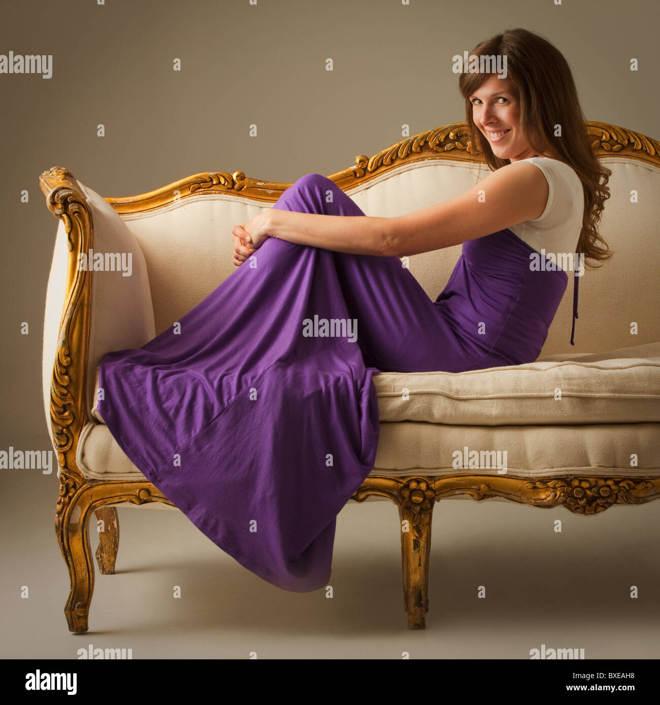 Elegant woman sitting on antique sofa Stock Photo