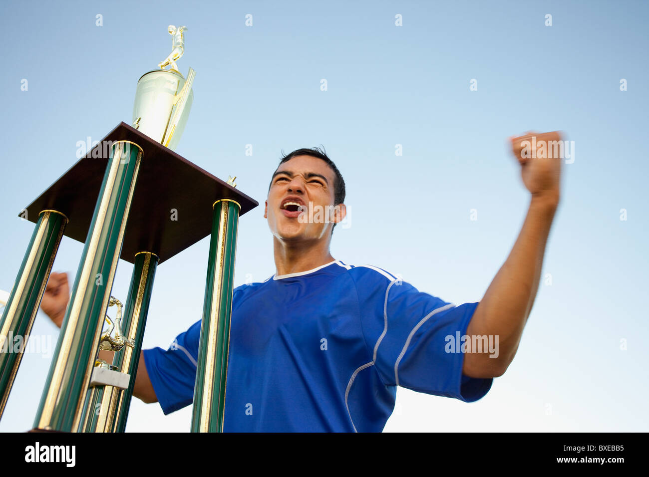 Trophy in front of cheering soccer player Stock Photo