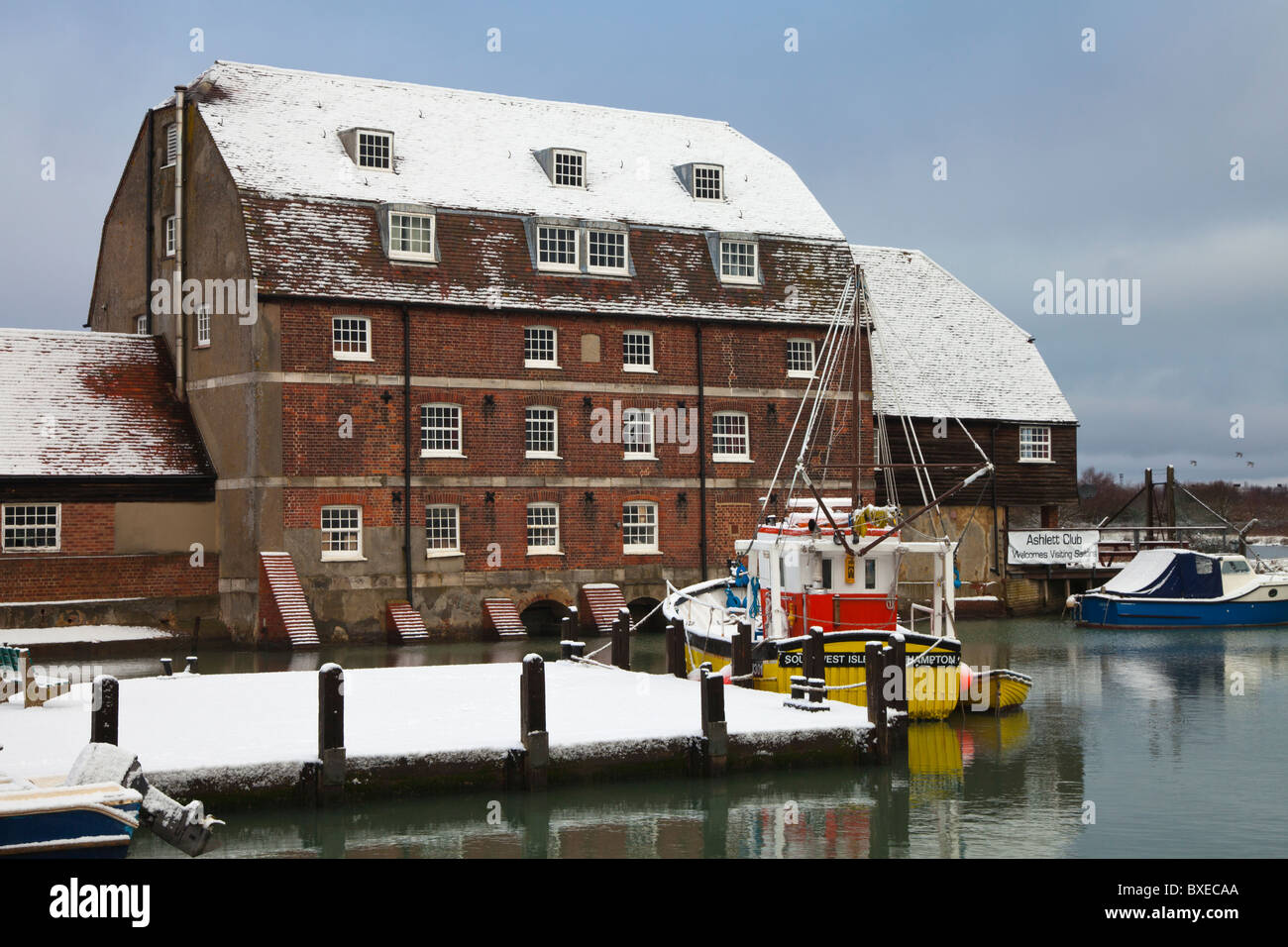 Snow covered yellow commercial shell fishing trawler moored alongside quay at Ashlett Mill Southampton Water Stock Photo