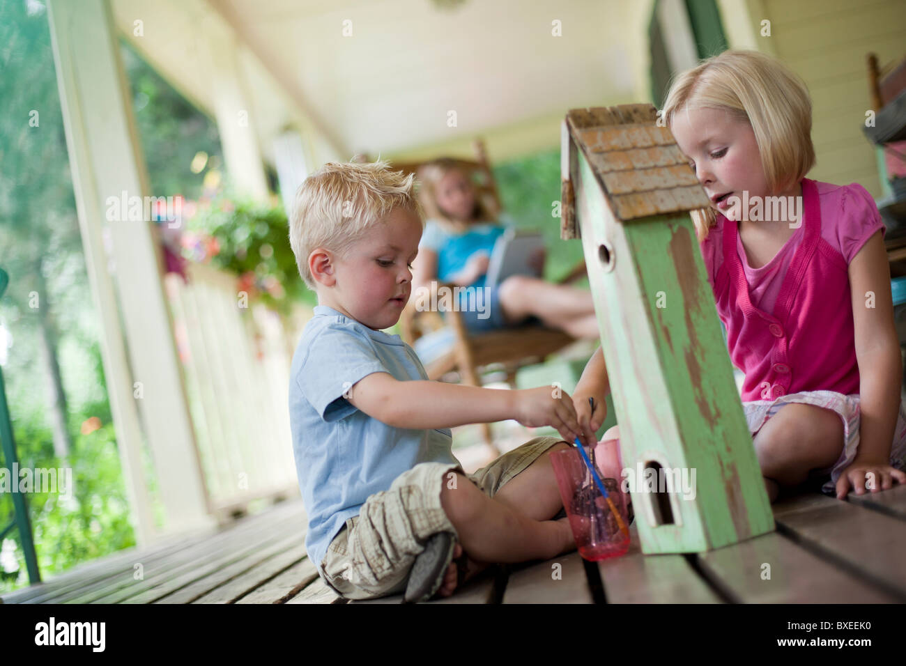 Brother and sister painting birdhouse together Stock Photo - Alamy
