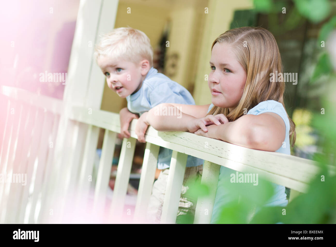 Brother and sister gazing over porch railing Stock Photo - Alamy