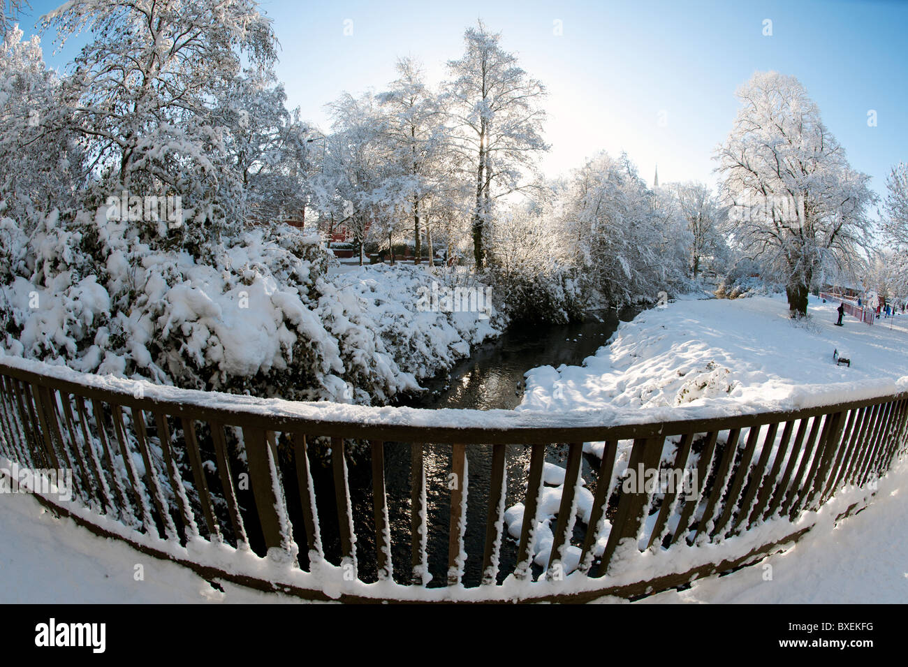 Winter snow scene in park land with trees steam and bridge Stock Photo