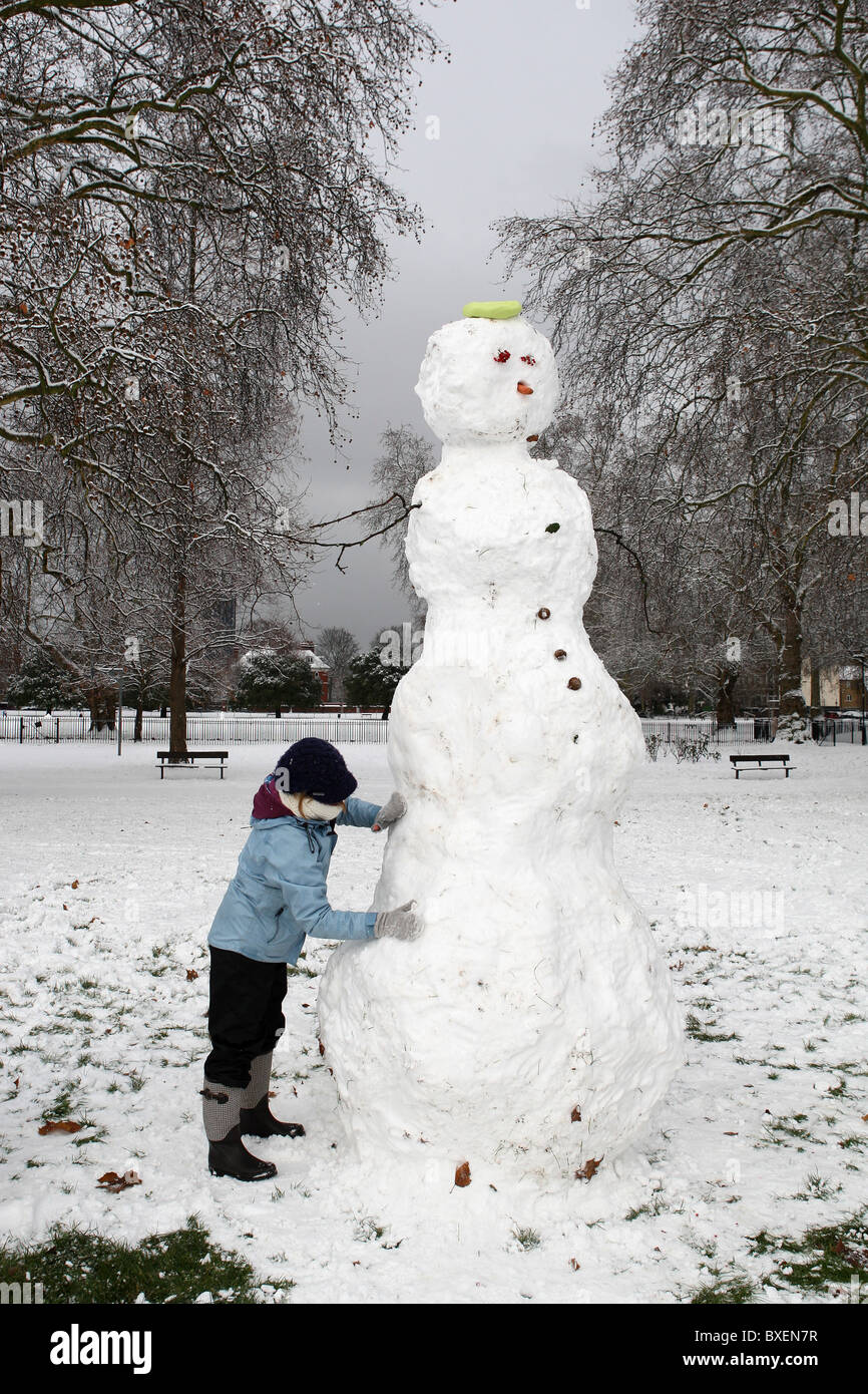 A woman is making a snowman after heavy snowfall in Kennigton Park, London, UK on December 18th, 2010. Stock Photo