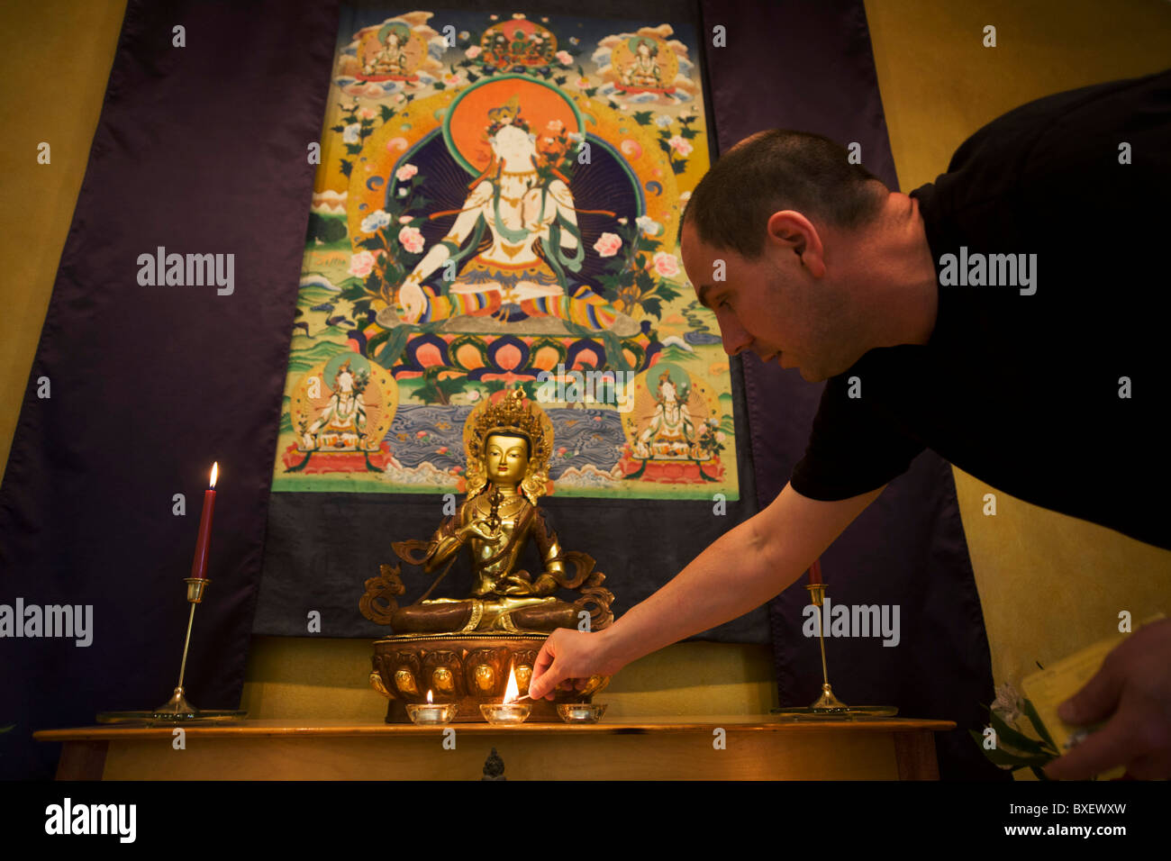 The Buddhist monk Nagasiddhi lights candles in the Shrine Room at the Rivendell Buddhist Retreat Centre, East Sussex, England. Stock Photo