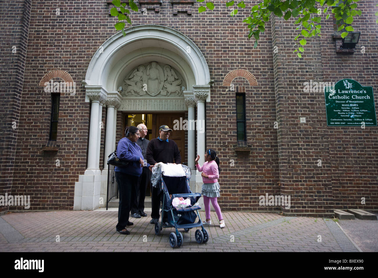 Catholic priest bids goodbye to parish family after morning Mass at St. Lawrence's Catholic church in Feltham, London. Stock Photo