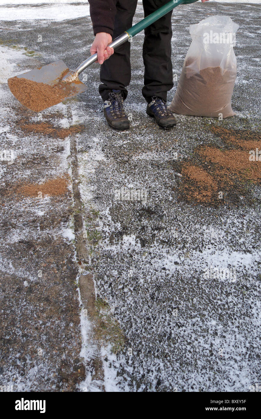 Caucasian Man Applying Rock Salt ( Gritting ) to an Icy Path and Driveway, UK MODEL RELEASED Stock Photo
