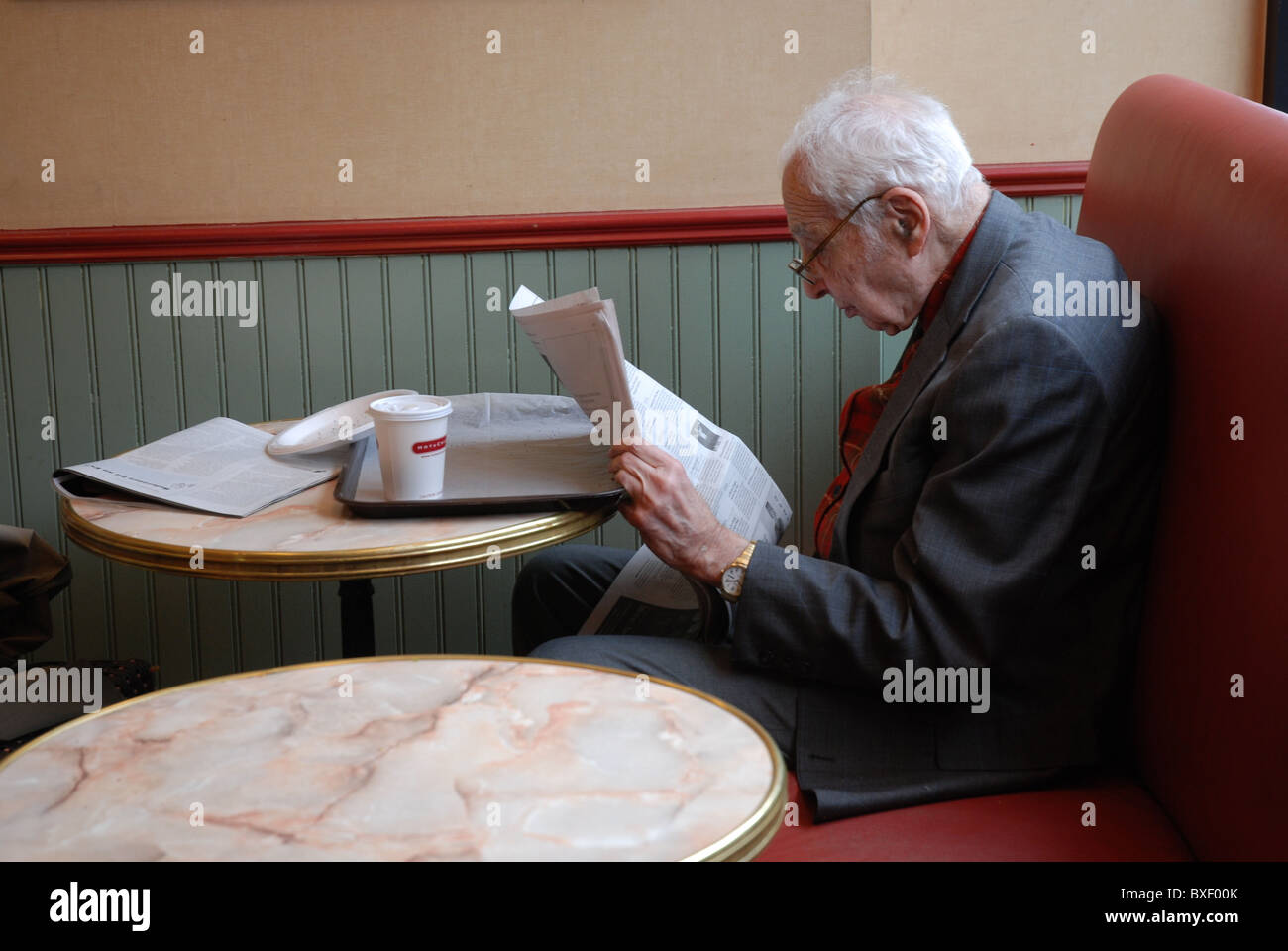 One old American Man reading Newspaper in a Cafe Restaurant in Manhattan Stock Photo
