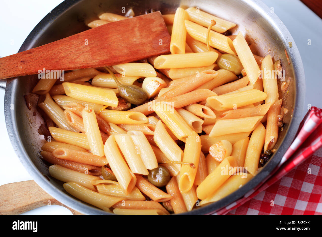 Pasta tubes with garlic and capers in a saucepan Stock Photo