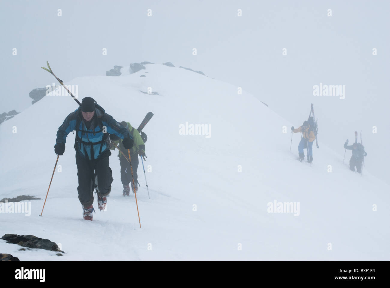 Four free skiers climbing up a snowy mountain side in Lyngen, Norway Stock Photo