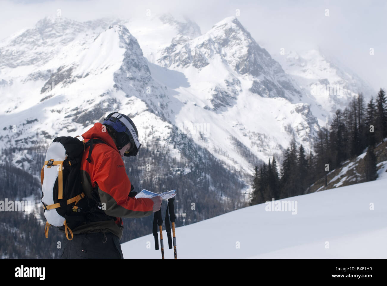 Free skier reading a map and admiring the wintery mountain landscape at ...