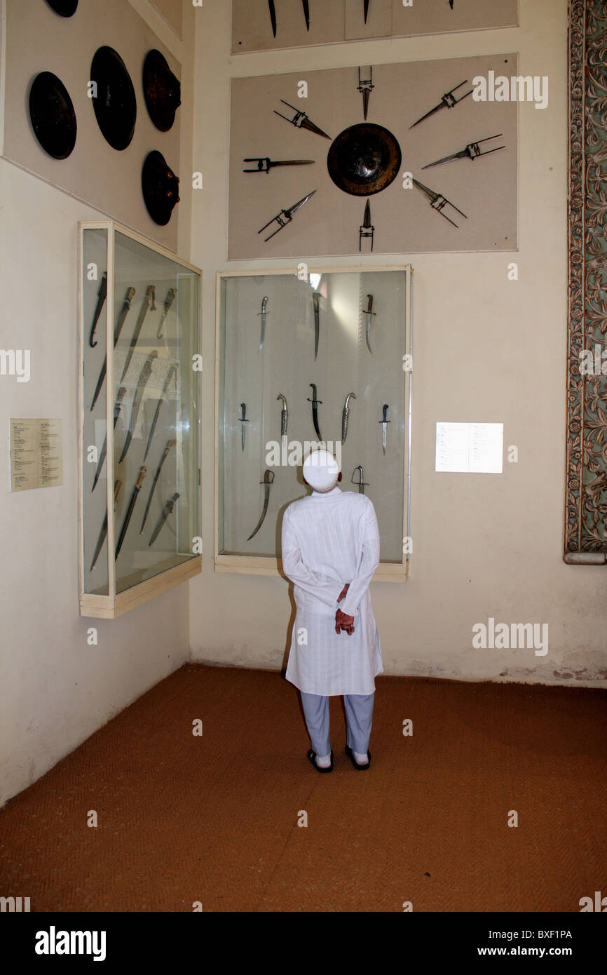 Indian man wearing Nehru suit looks at collection of antique swords, daggers and other weapons, Chowmahalla Palace Hyderabad Stock Photo