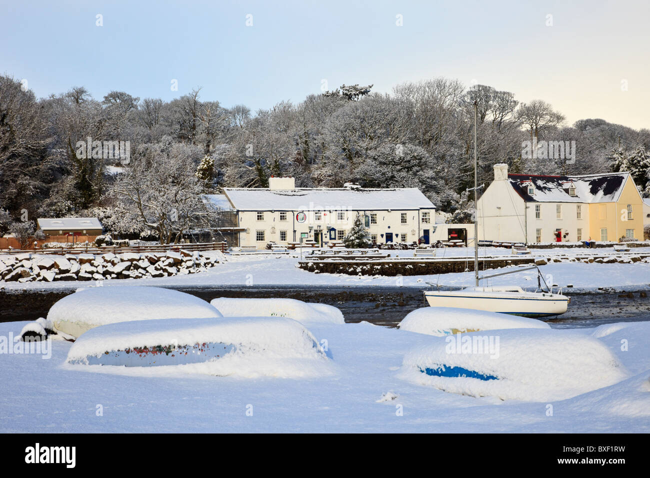 Snow scene with upturned boats on snowy coast in winter December 2010. Red Wharf Bay (Traeth Coch), Isle of Anglesey, North Wales, UK. Stock Photo