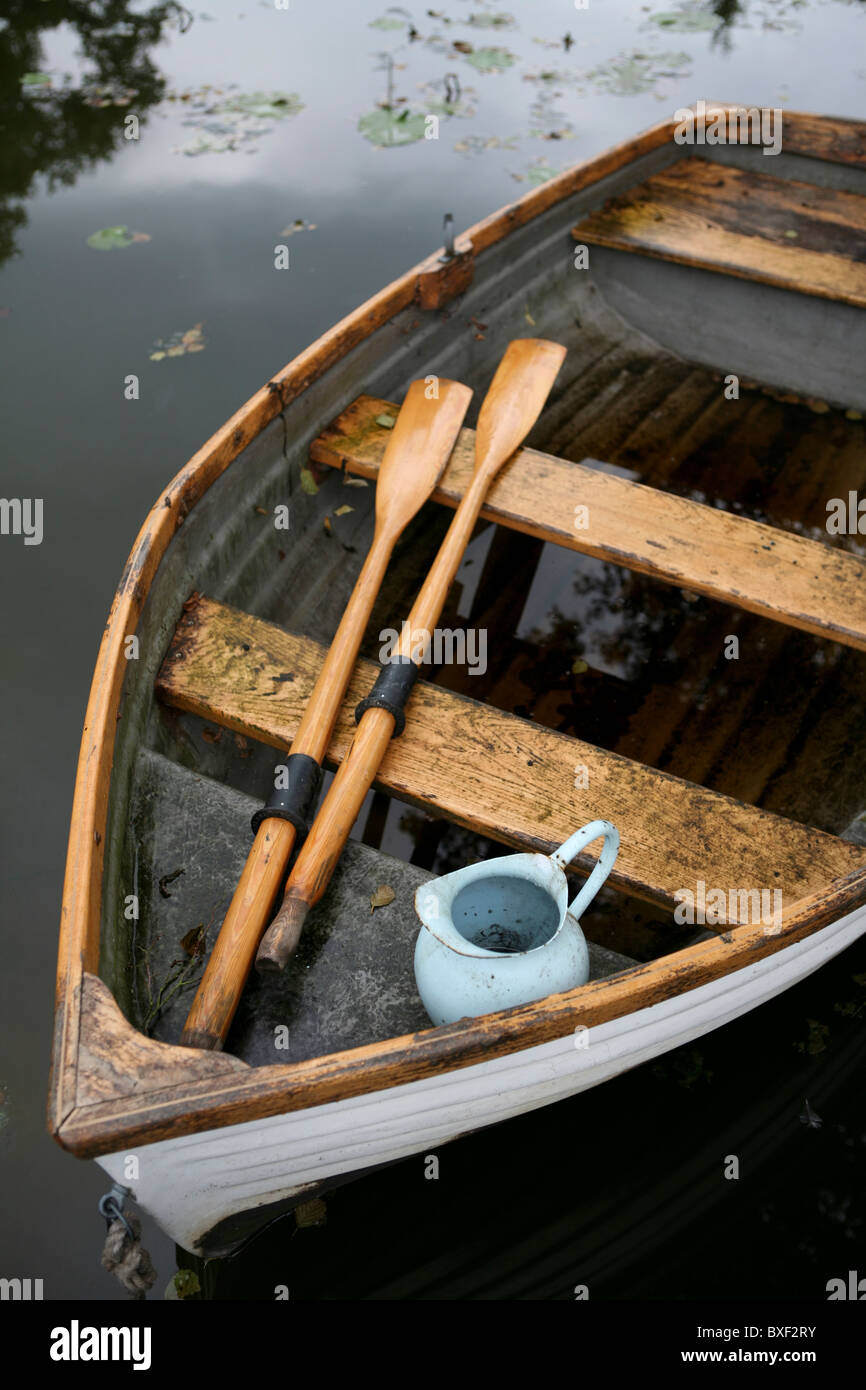 An old weather-beaten wooden row boat with oars and water jug, view from above. Stock Photo