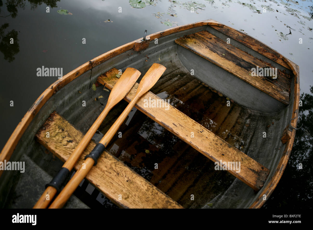 An old weather-beaten wooden row boat with oars, view from above. Stock Photo