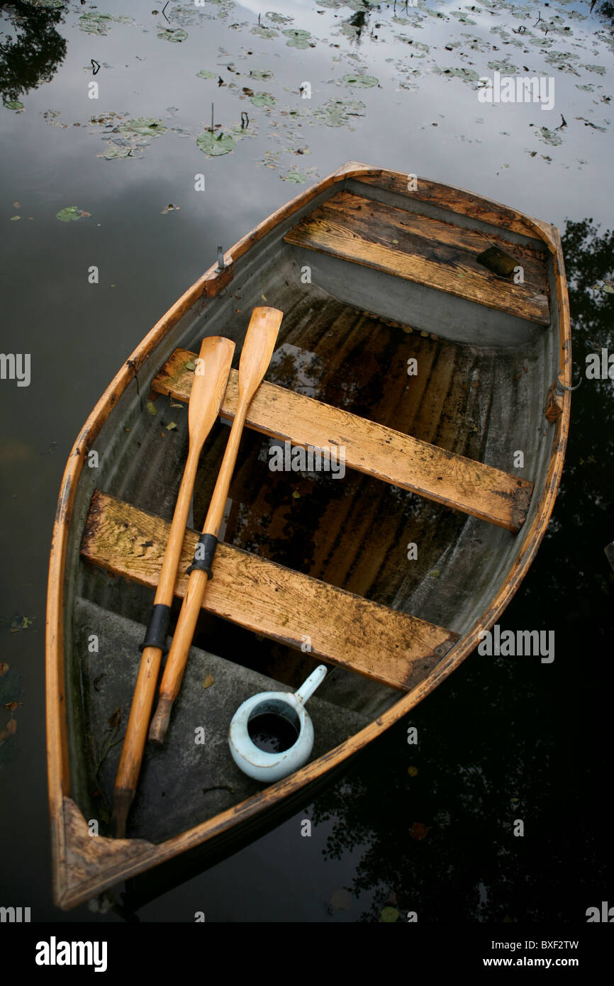 An old weather-beaten wooden row boat with oars and water 