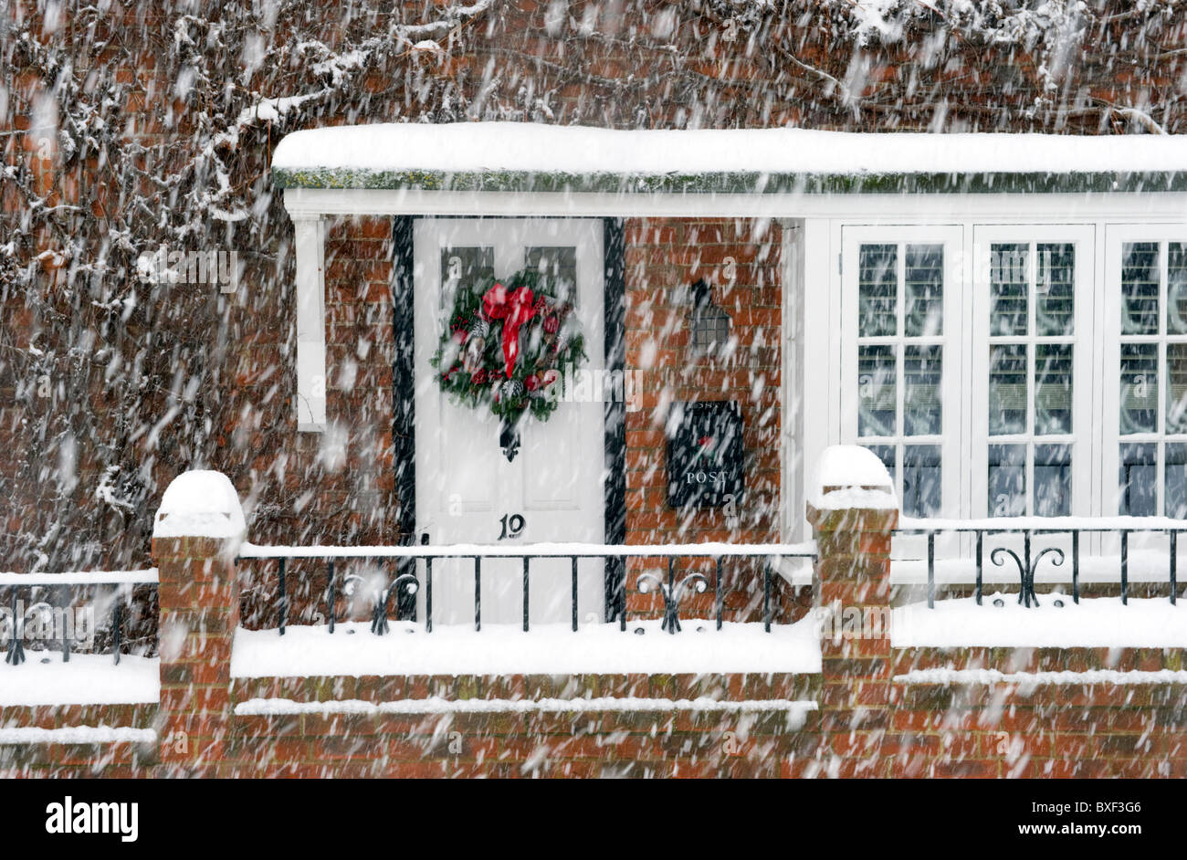 front door Christmas decoration wreath obscured by a falling Winter snow blizzard Stock Photo