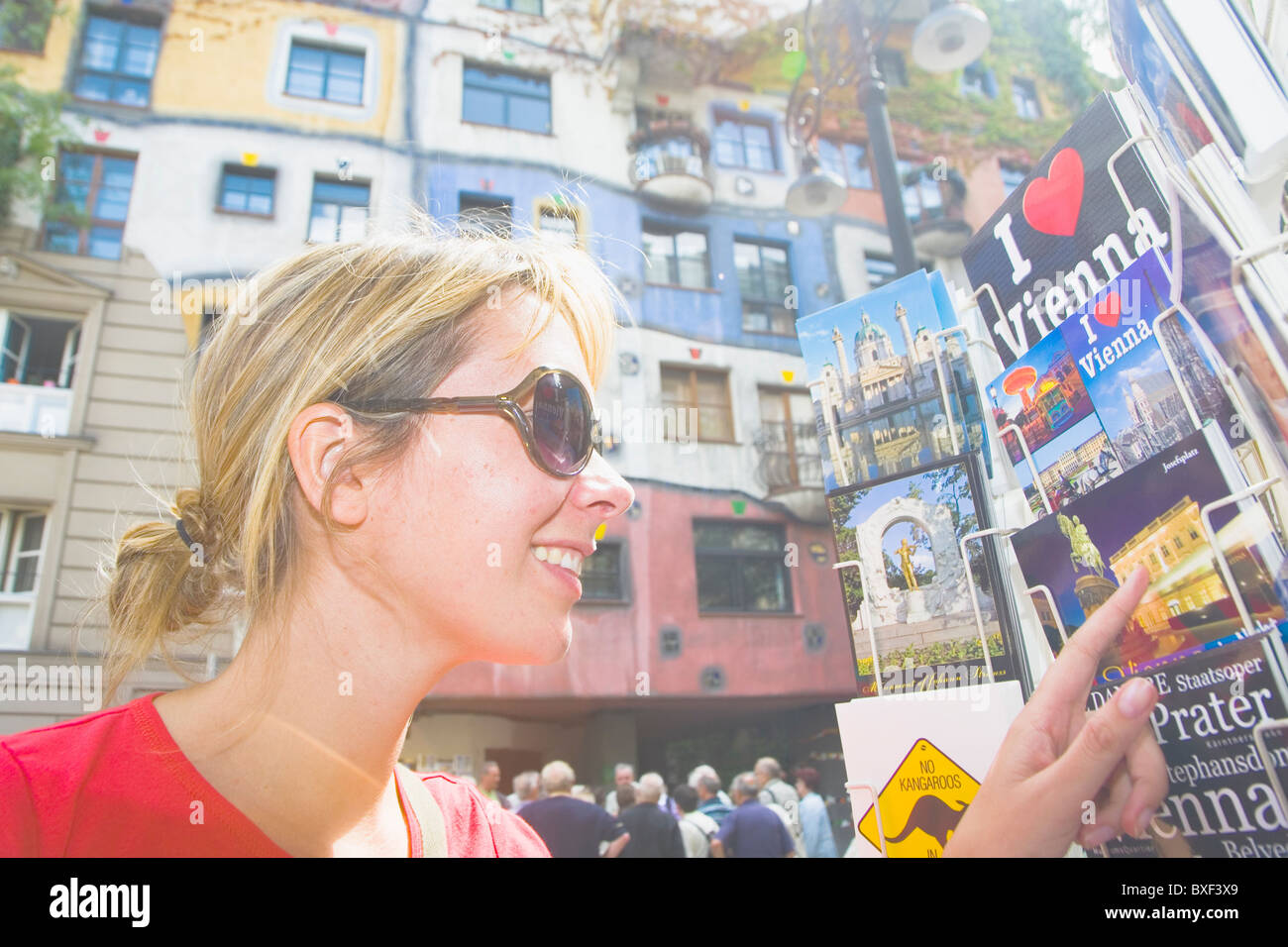 Woman looking at postcards in Vienna with the famous hundertwasserhaus in the background Stock Photo