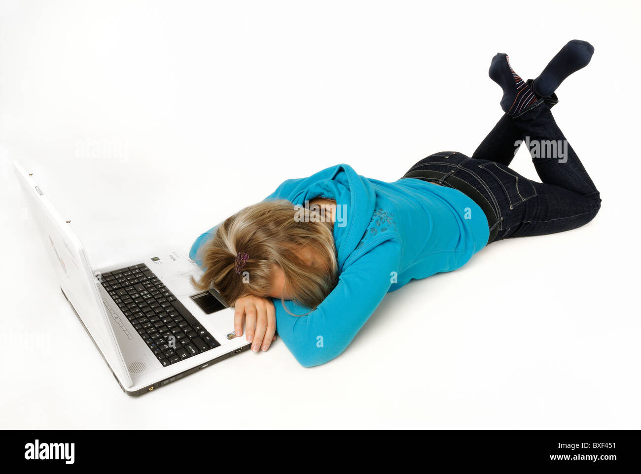 Young woman lying in front of a laptop computer, asleep Stock Photo