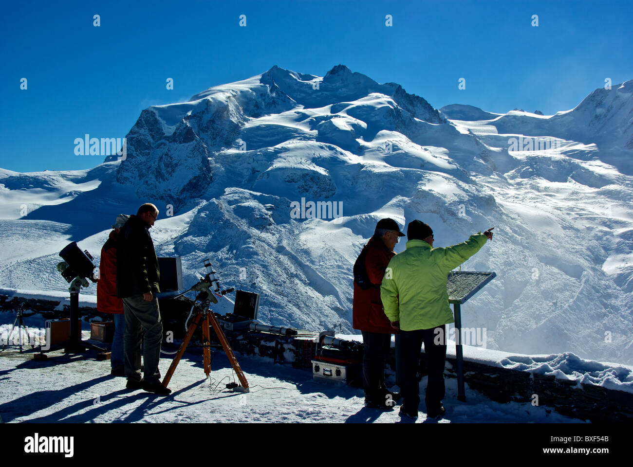 Astronomers telescopes scientific instruments tourists Gornergrat alpine train station snow covered viewing platform Zermatt Stock Photo