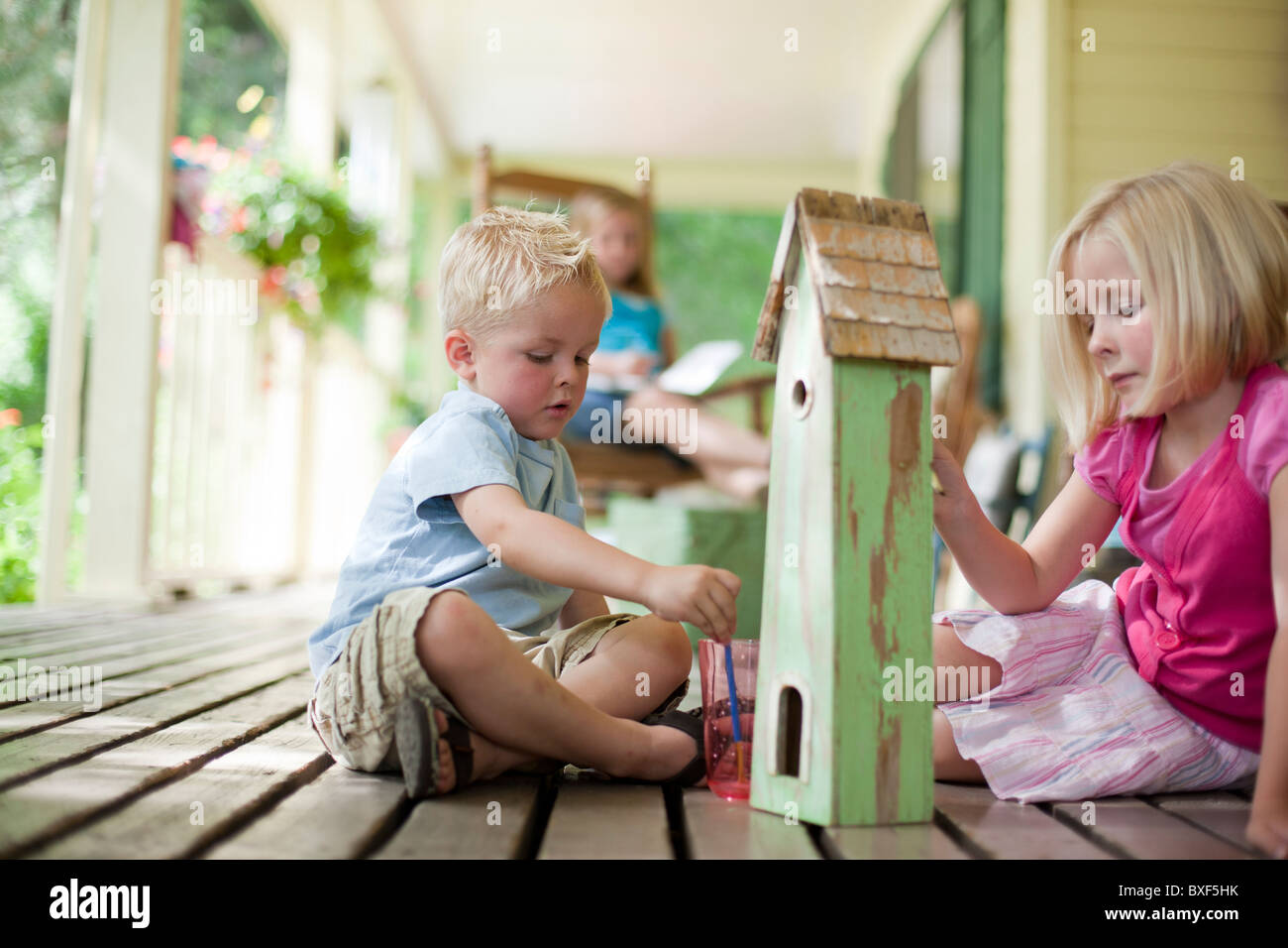 Brother and sister painting birdhouse together Stock Photo - Alamy
