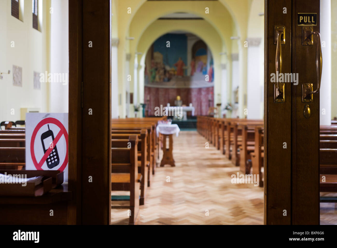 No mobile phones sign and interior of the 1930s built St. Lawrence's Catholic church in Feltham, London. Stock Photo