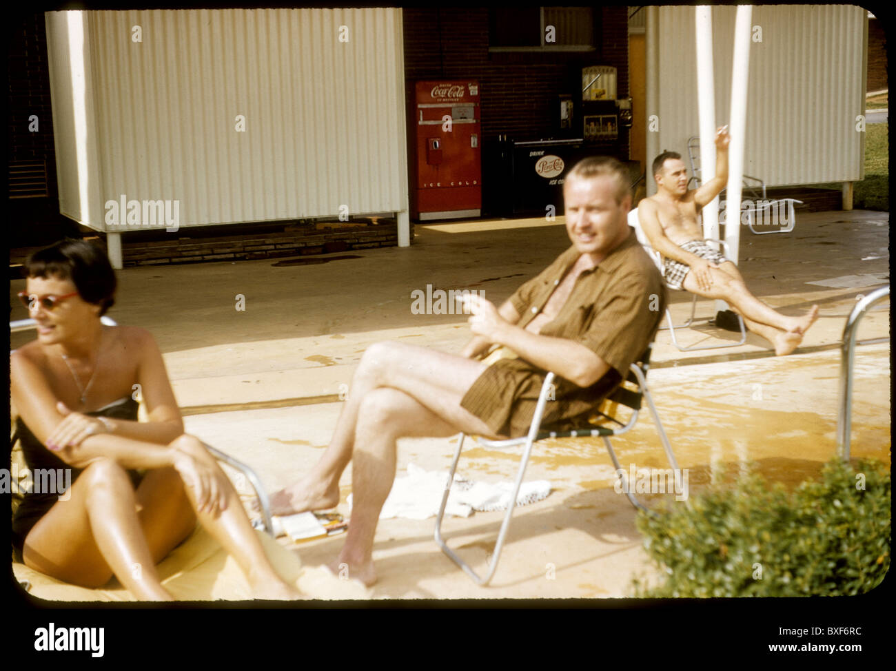 two men and one woman relaxing poolside swimming pool motel coca cola machine 1959 1950s outdoors vacation travel summer black Stock Photo