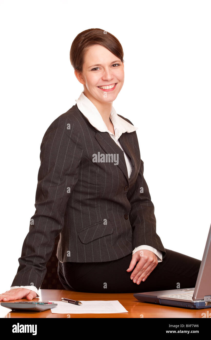 Attractive happy business woman sitting in office at desk. Isolated on white background. Stock Photo