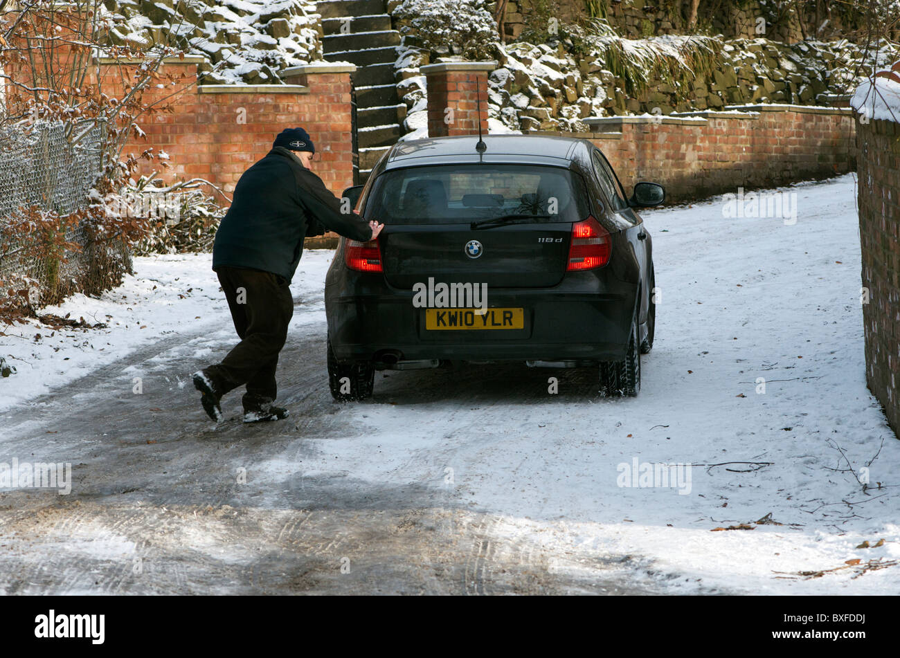 man pushing car up hill in snow and ice Stock Photo Alamy