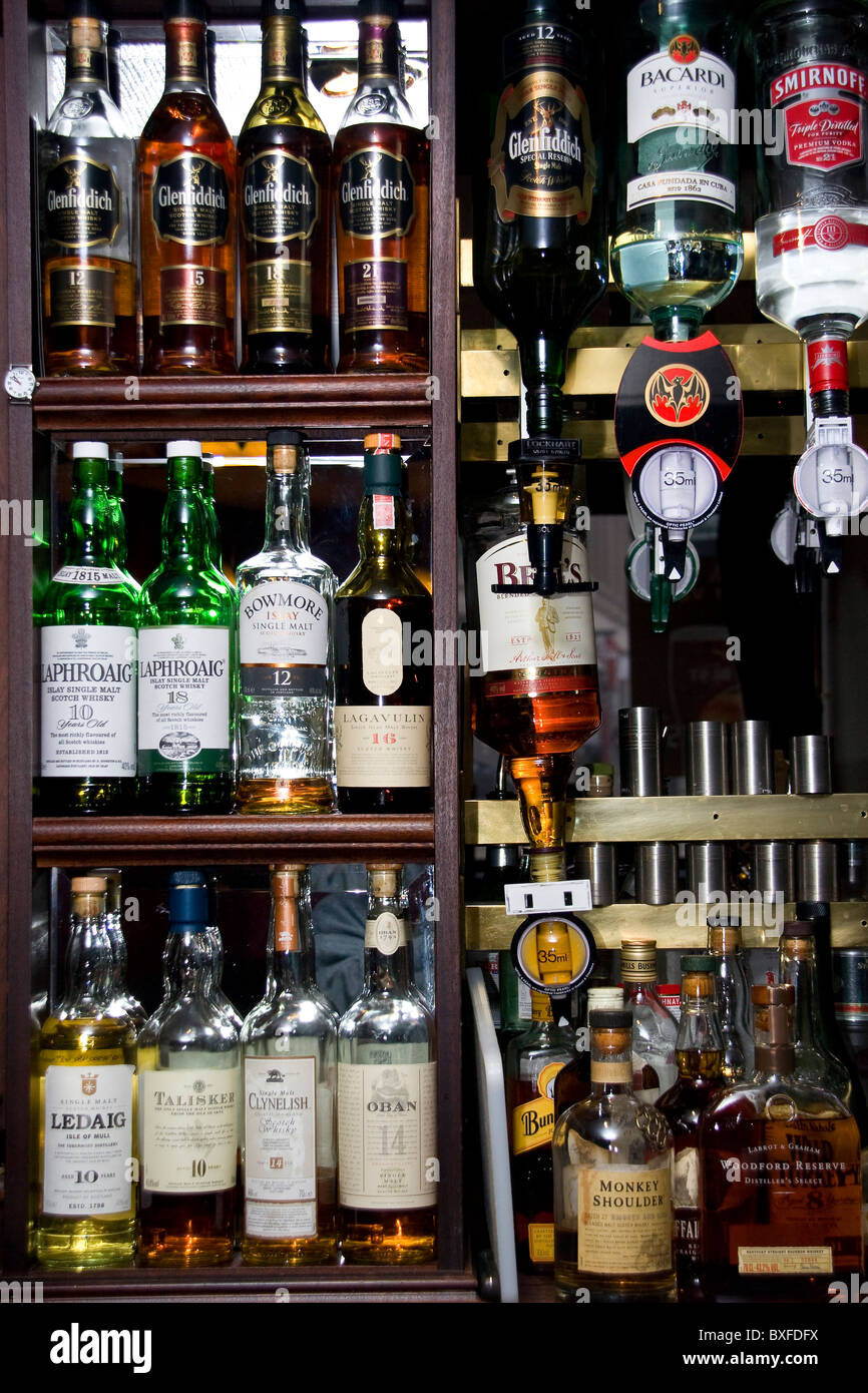A row of bottles displaying many different brands of Scottish Whiskeys behind the bar inside a local pub in Dundee,UK Stock Photo