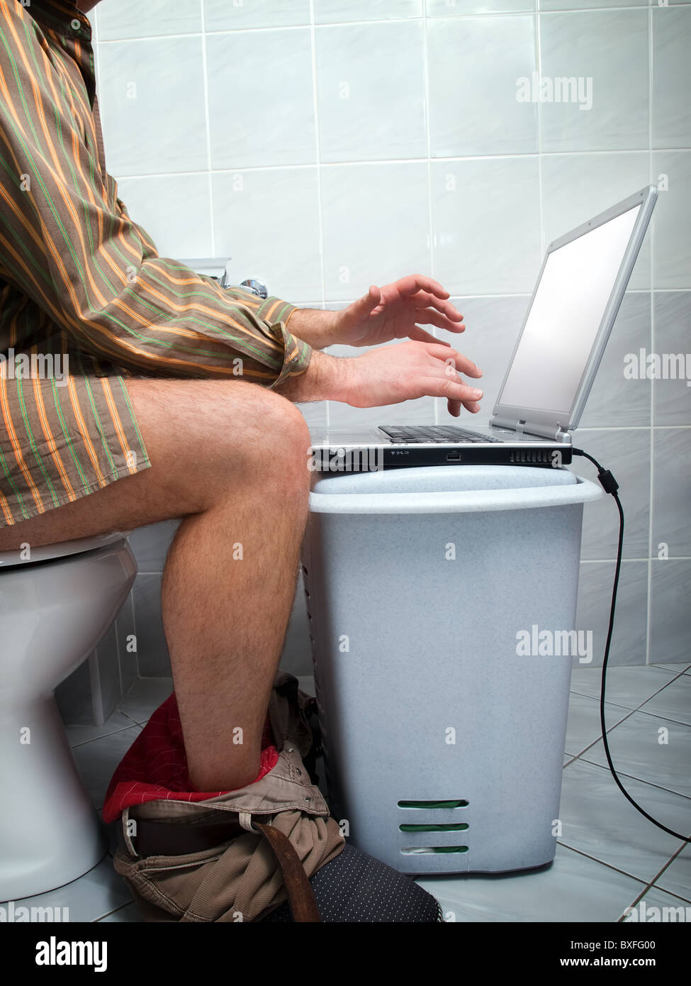 Conceptual view of an internet addict during "calling of nature" in the toilet. Stock Photo