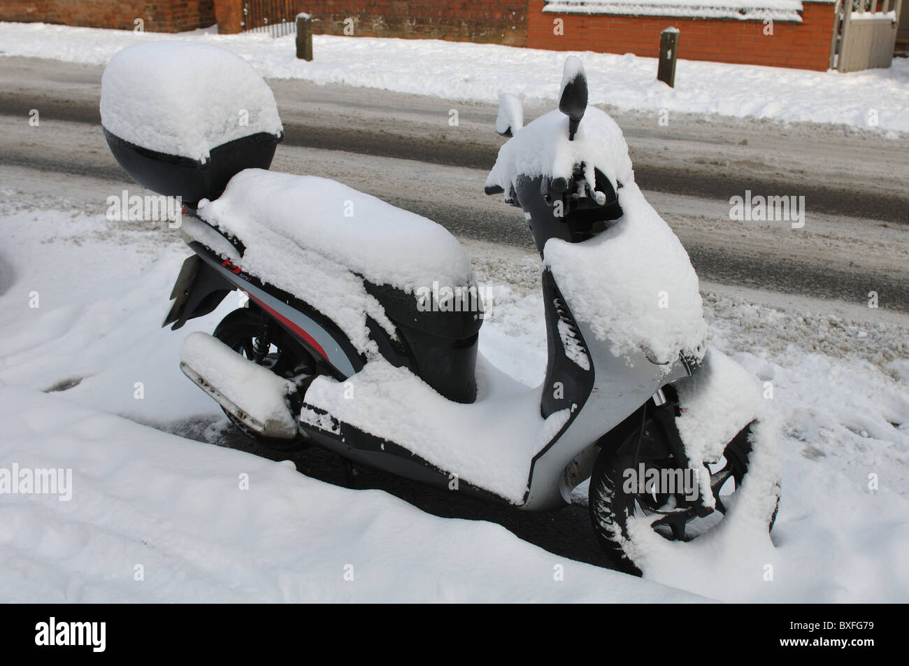 Parked motor scooter with snow on Stock Photo