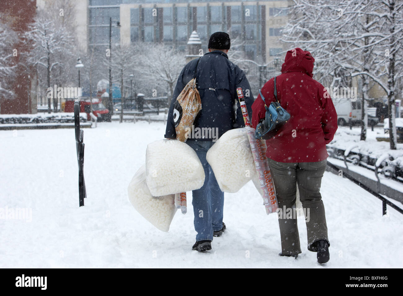 couple out christmas shopping walking through deep snow on a cold snowy winters day Belfast Northern Ireland Stock Photo