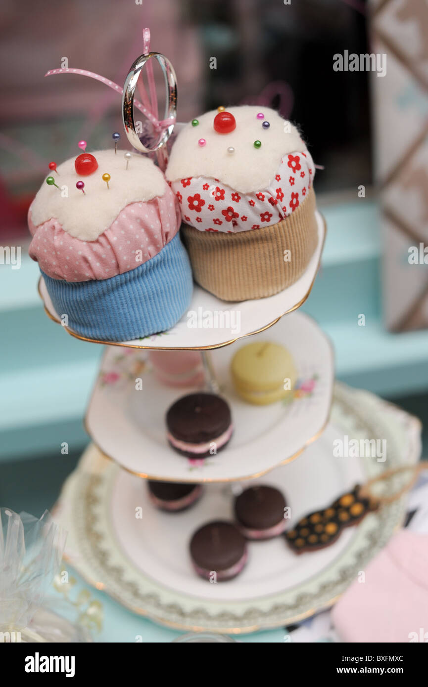 Oldfashioned cake stand with fancy fabric pin cushion iced cakes in
