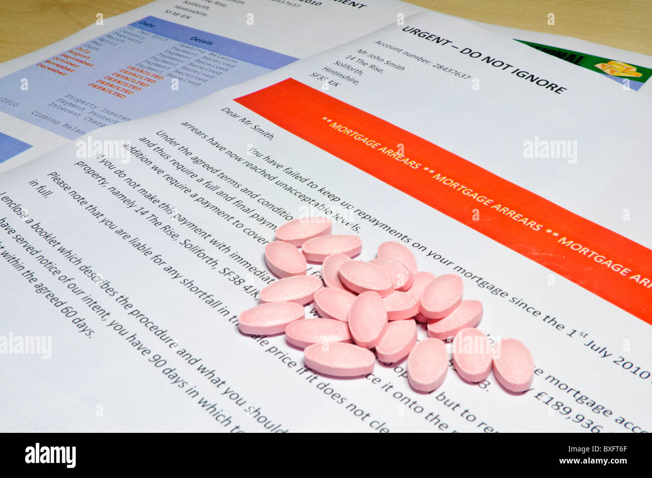 Pile of tablets on a bank letter informing customer of Mortgage Arrears and repossession  with bank statement Stock Photo