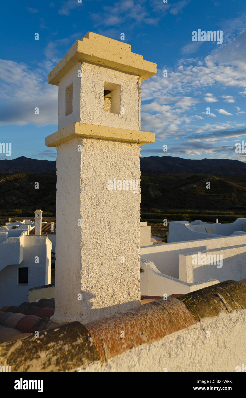 A view of a chimney and rooftops at sunset, Alfaix, Almeria, Spain. The light in Alfaix, Almeria was lovely when I took this photo of the chimney. Stock Photo