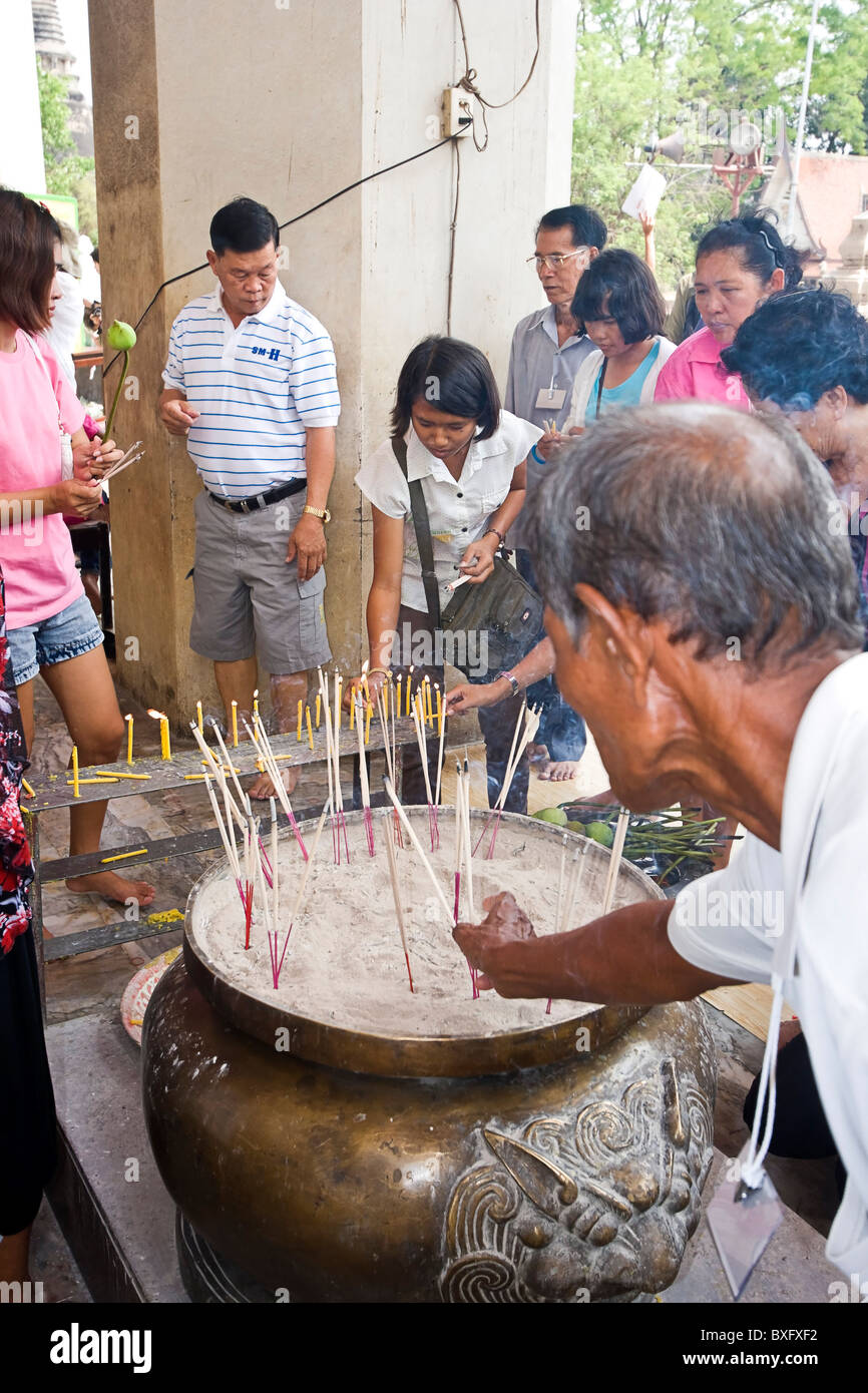 Buddhist worshipers light incense as offerings to Buddha at Wat Phra Sri Sanpetch Buddhist
