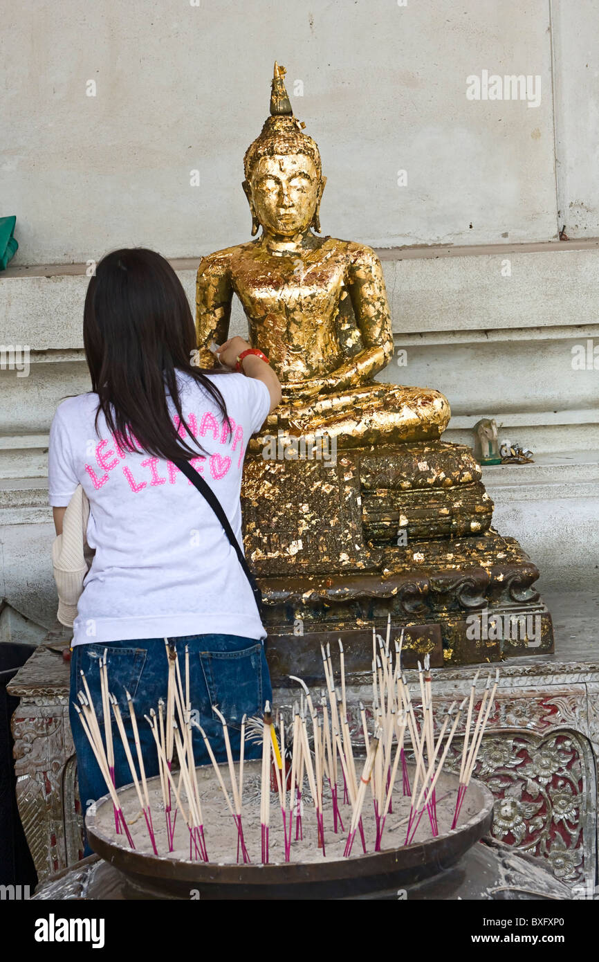 Buddhist worshipers light incense as offering to Buddha at Wat Phra Sri Sanpetch Buddhist temple
