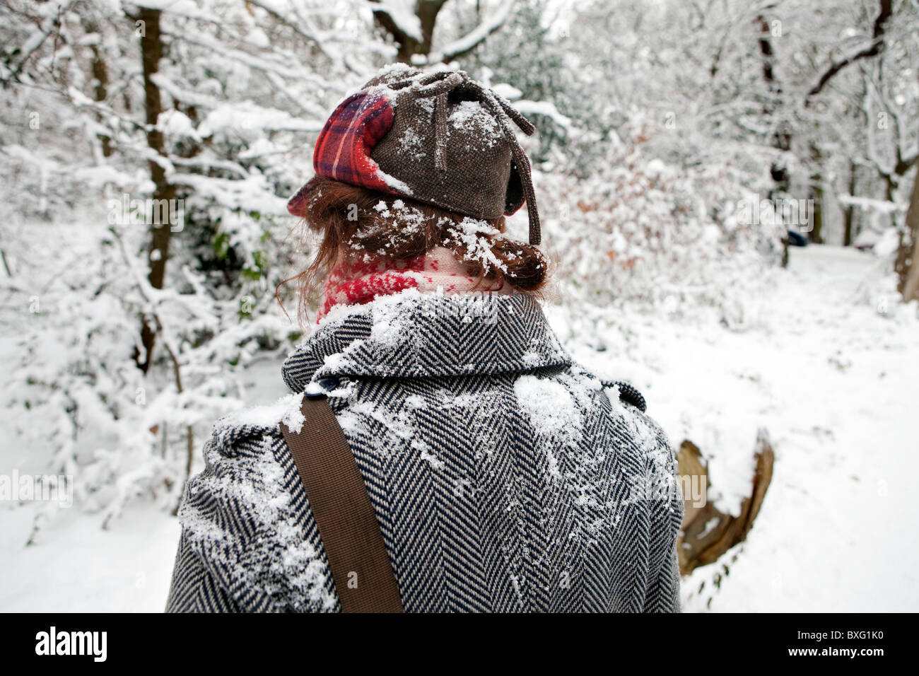 Rear view of woman walking in snowy landscape covered in snow. Stock Photo