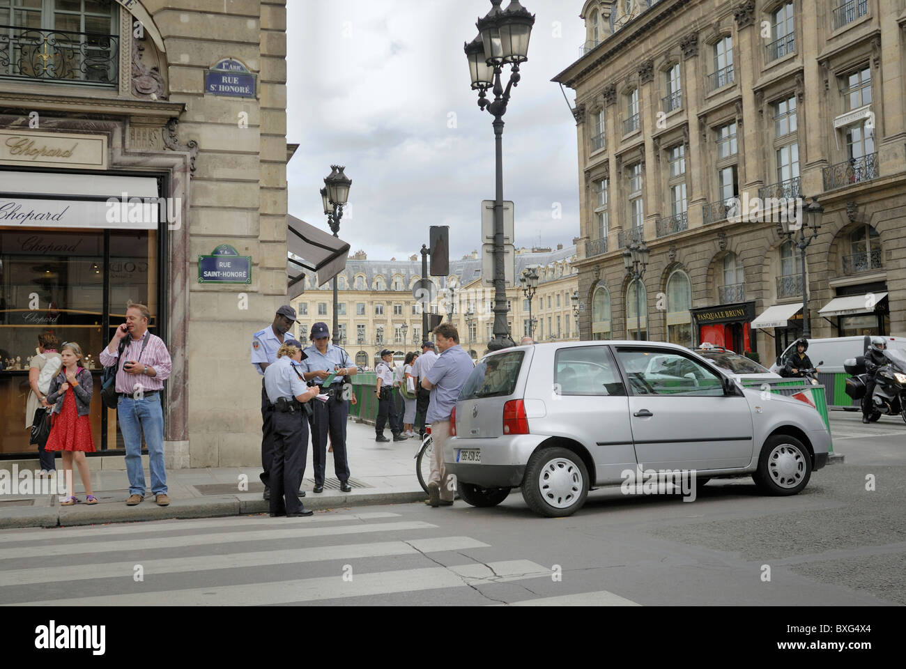 A man stopped on Rue Saint-Honore, receives a traffic ticket from three bylaw officers on the streets of Paris, France. Stock Photo