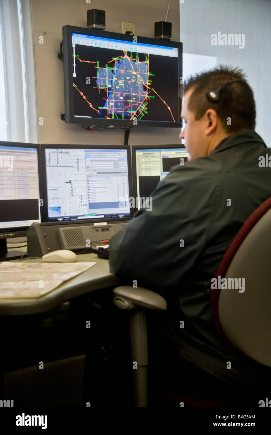 A police dispatcher works at a computer console handling incoming phone calls and directing police activity in Santa Ana, CA. Stock Photo