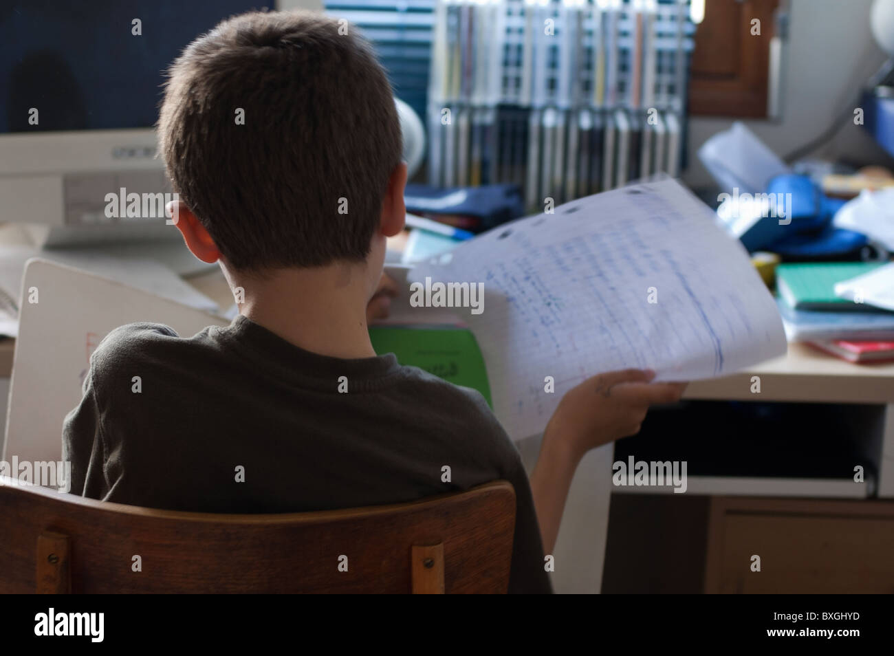 Boy sitting at his desk and doing his homework in his bedroom. Stock Photo